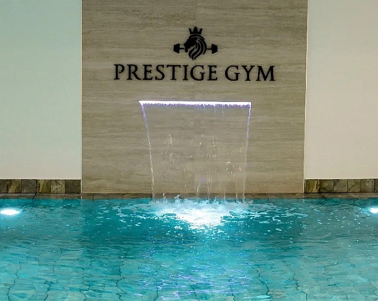 A sheet of water falling into the pool beneath the club's name.