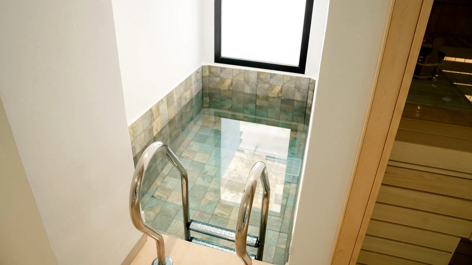 The jacuzzi, set into stone with a glass balustrade and handrail.